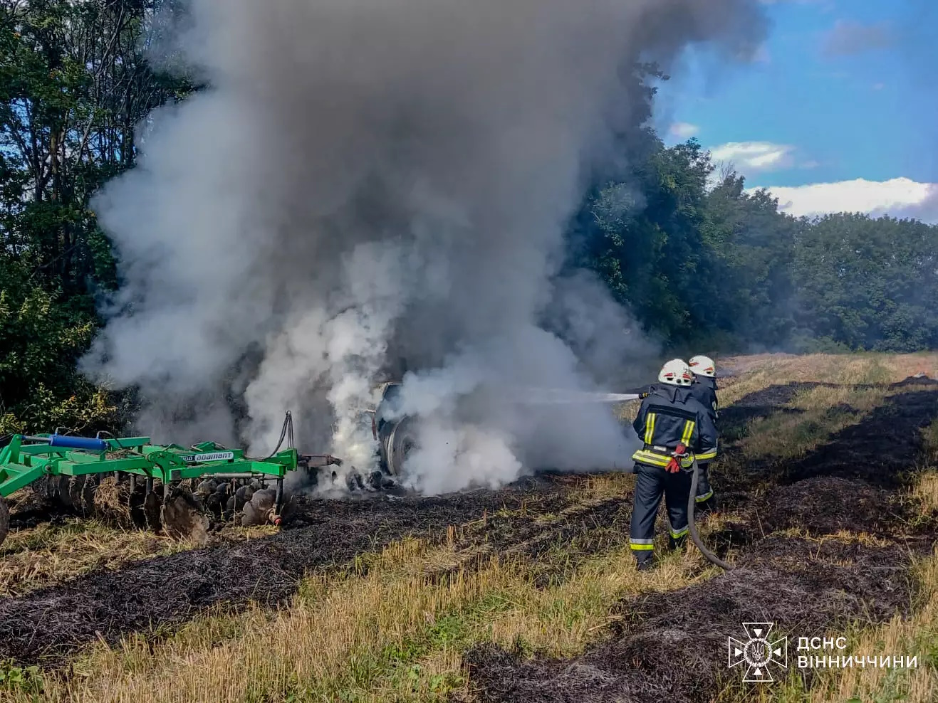 Пожежники гасять трактор, який горить на полі у Вінницькій області