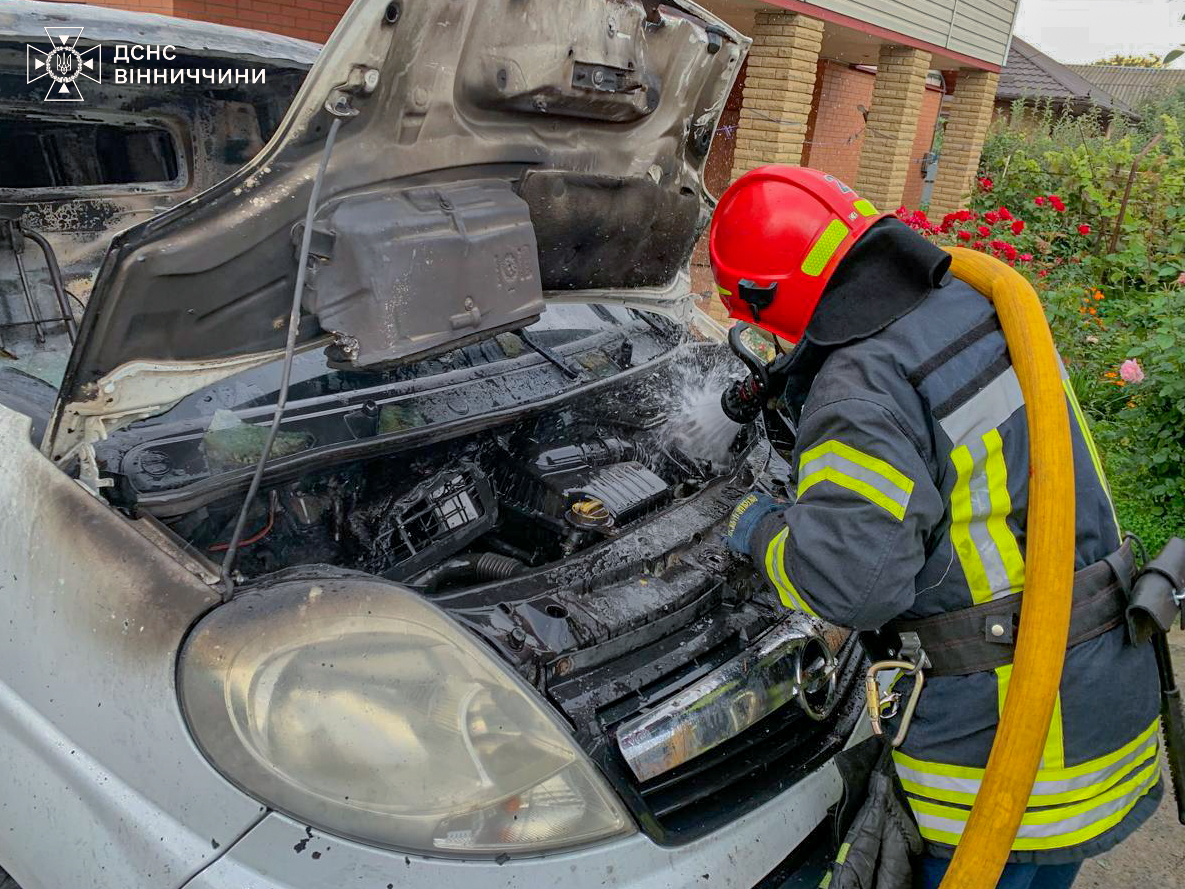 Пожежник гасить вогонь під капотом автомобіля у Вінницькому районі