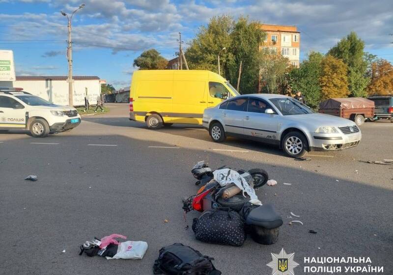 Перевенутий мопед лежить на дорозі, речі висипались, поруч знаходиться легковик та автомобіль поліції