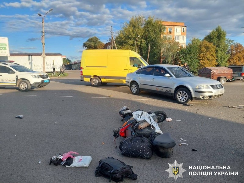 Перевенутий мопед лежить на дорозі, речі висипались, поруч знаходиться легковик та автомобіль поліції