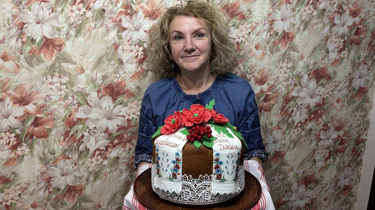 «Хочеться передати шматочок своєї душі»: майстриня з Вінниччини пече традиційні короваї для українських захисників Лід: Майстриня Людмила Чайнюк із міста Гайсин на Вінниччині вже понад два роки створює традиційні українські короваї для військовослужбовців ЗСУ. Поєднавши родинні секрети мами й бабусі із сучасними кондитерськими техниками, жінка випекла й передала на фронт уже понад 80 короваїв. Своїми виробами вона прагне подарувати захисникам і захисницям домашнє тепло та шматочок рідної душі. Шлях до майстерності та сімейні традиції: Від дитячого захоплення до професії: Випікати Людмила почала змалку — у 10 років спробувала спекти торт для мами. Після закінчення педагогічного інституту працювала вчителькою біології та географії, а згодом, вийшовши на пенсію, повністю присвятила себе улюбленій справі. Відродження традицій: Живучи в селі Носівці, майстриня опанувала давні обряди випікання весільних короваїв, які супроводжувалися старовинними піснями та благословенням. Згодом вона вдосконалила свої навички на майстер-класах і тепер створює справжні витвори кулінарного мистецтва. Традиційні символи у декор: Усі елементи оздоблення короваїв мають глибоке значення: колоски символізують достаток, маки та троянди — красу, калина — Україну, а рушнички й польові квіти додають виробам особливого затишку. Особливості випічки для фронту: Довговічність тіста: Для захисників Людмила готує випічку виключно за спеціальним коровайним рецептом. Таке тісто чудово зберігається до двох тижжя, не втрачає свіжості, а за потреби його можна заморозити й куштувати порціями. Волонтерська ініціатива: З 2023 року майстриня готує короваї щотижня за власний кошт. Передає випічку через волонтерський центр у Гайсині або поштою, а звідти смаколики вирушають до бригад на передову. Іменна підтримка: У кожний виріб жінка вкладає думки про своїх колишніх учнів, друзів та знайомих, які нині боронять країну на передовій, аби нагадати їм про дім і принести радість до бойових бліндажів.